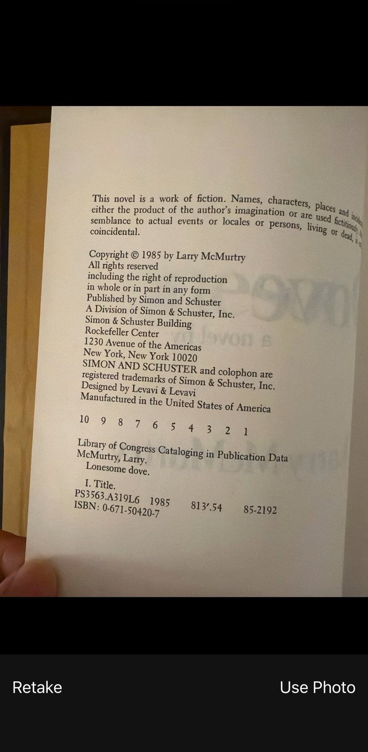The phone camera's Use Photo screen showing the copyright page of Lonesome Dove, with Simon and Schuster's details and the number line 10 9 8 7 6 5 4 3 2 1.